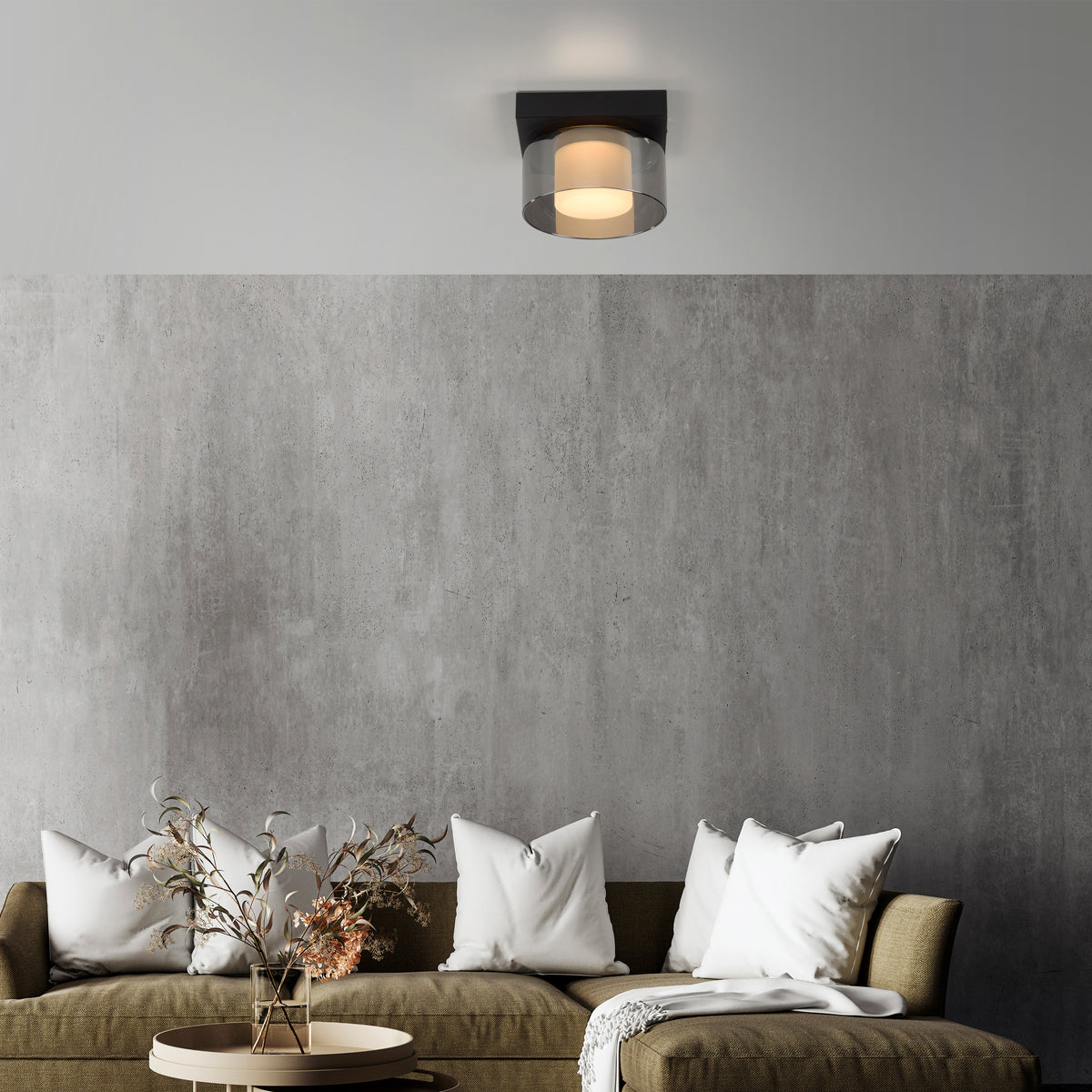 Mise en ambiance du plafonnier allumé au plafond devant un mur béton et un canapé.