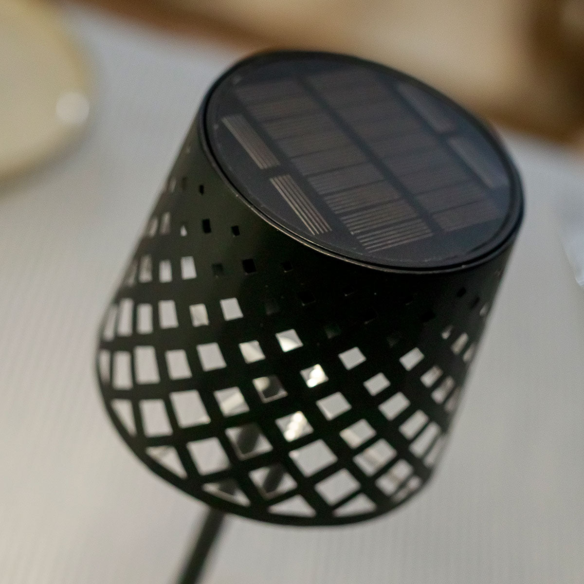 Détail du panneau solaire noir intégré au sommet de l'abat-jour ajouré.