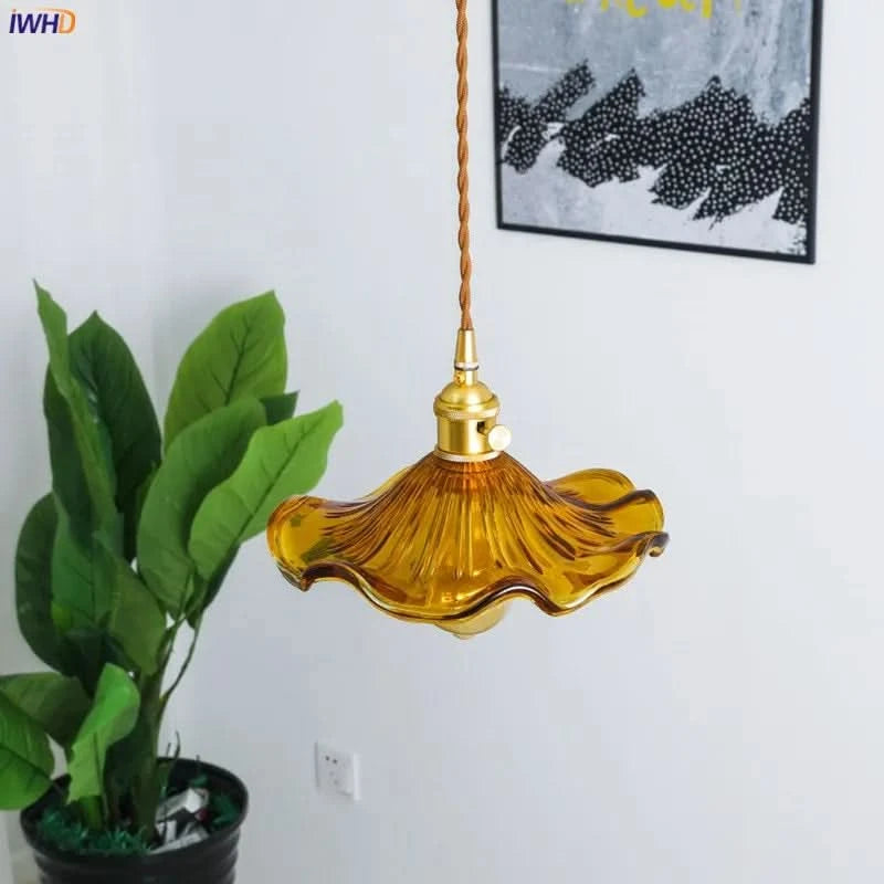 Détail d'une suspension ambre au verre ondulé près d'une plante verte en intérieur