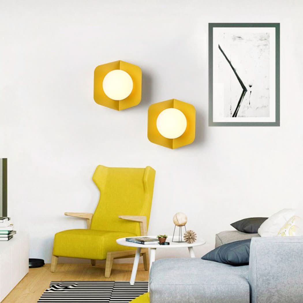 Ambiance salon jaune avec deux appliques et fauteuil assorti devant un tableau