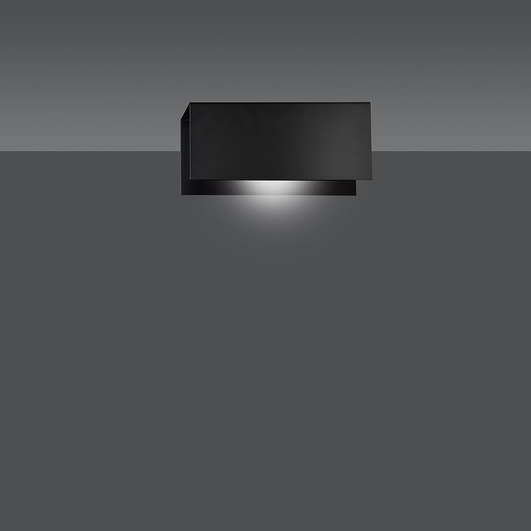 Vue en situation de l'applique noire éclairant un mur gris vers le bas