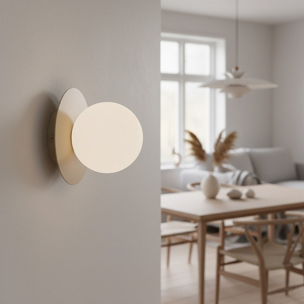 Mise en ambiance dans une salle à manger, applique allumée sur mur blanc cassé