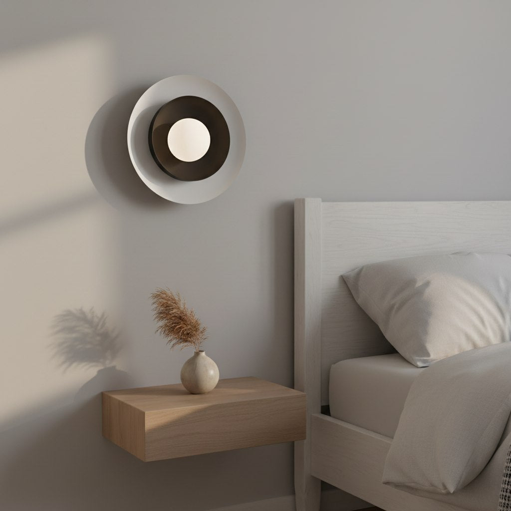 Mise en ambiance : applique allumée au-dessus d'une table de chevet en chambre.