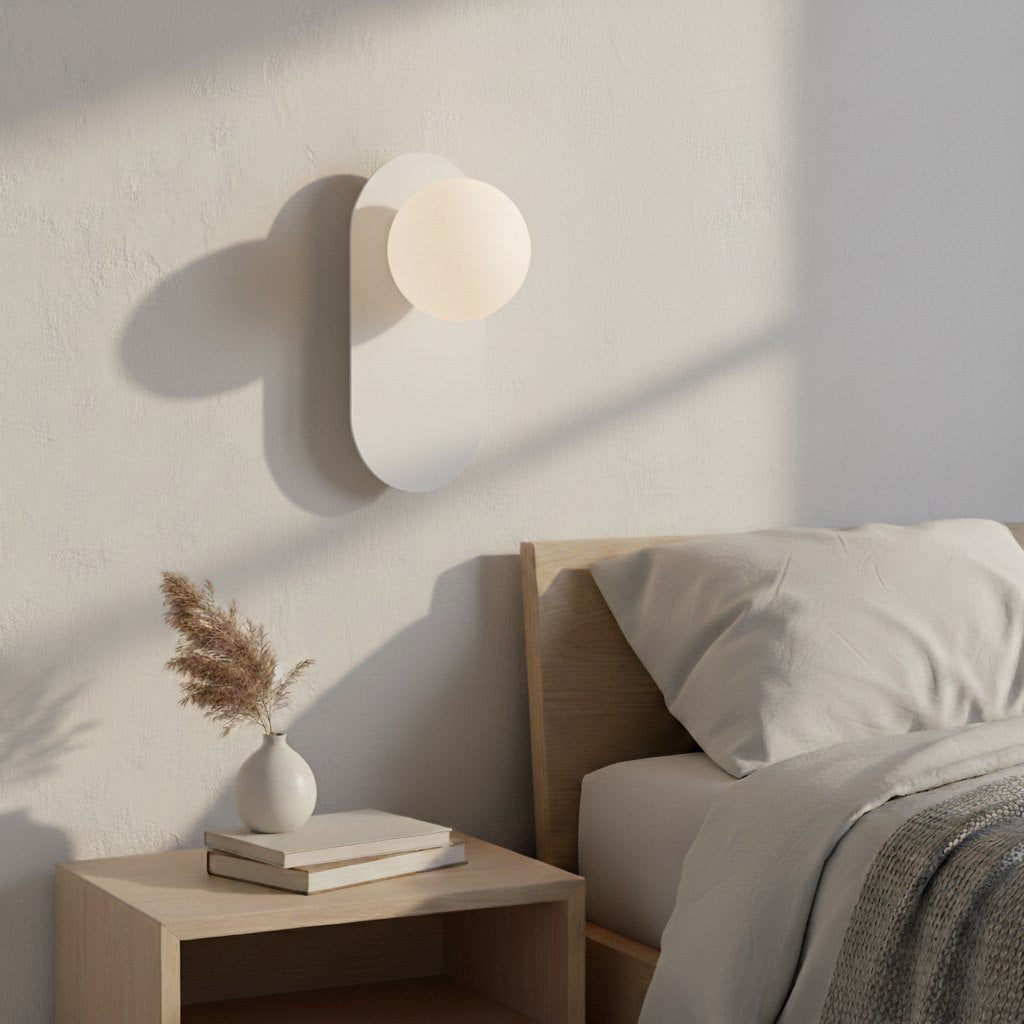 Mise en ambiance : luminaire allumé au-dessus d'une table de chevet en bois clair.