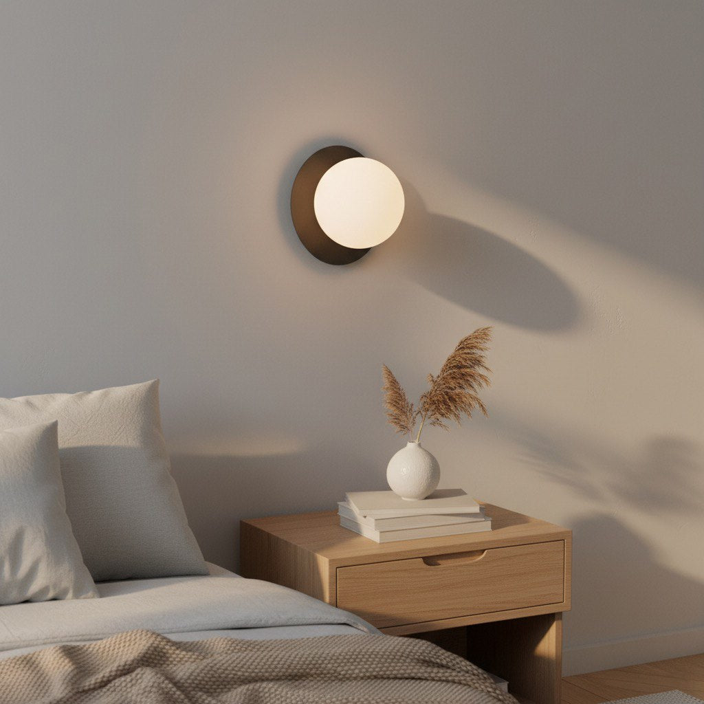 Ambiance chambre avec applique allumée au-dessus d'une table de chevet en bois clair