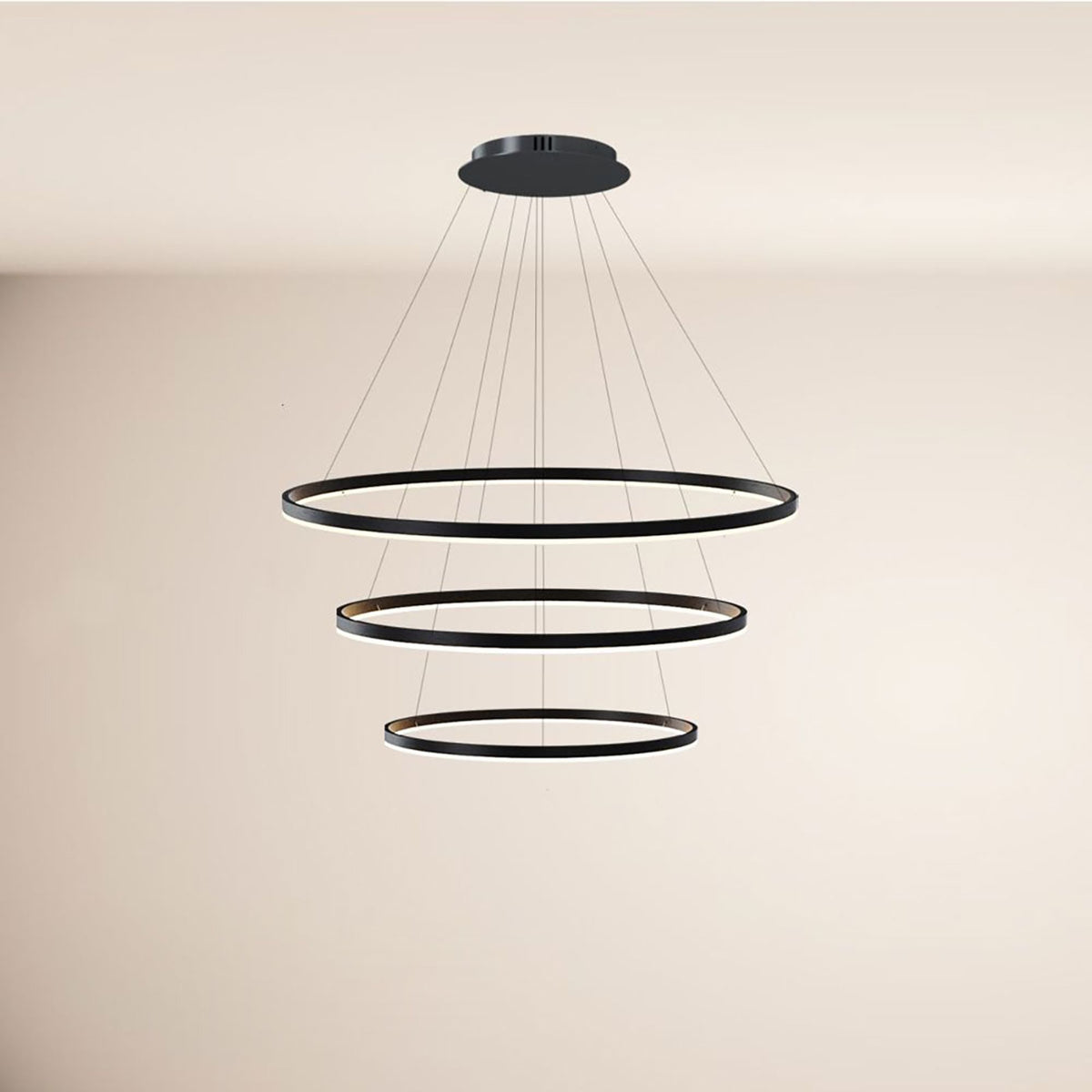Suspension noire à trois anneaux lumineux concentriques suspendus sous un plafond blanc