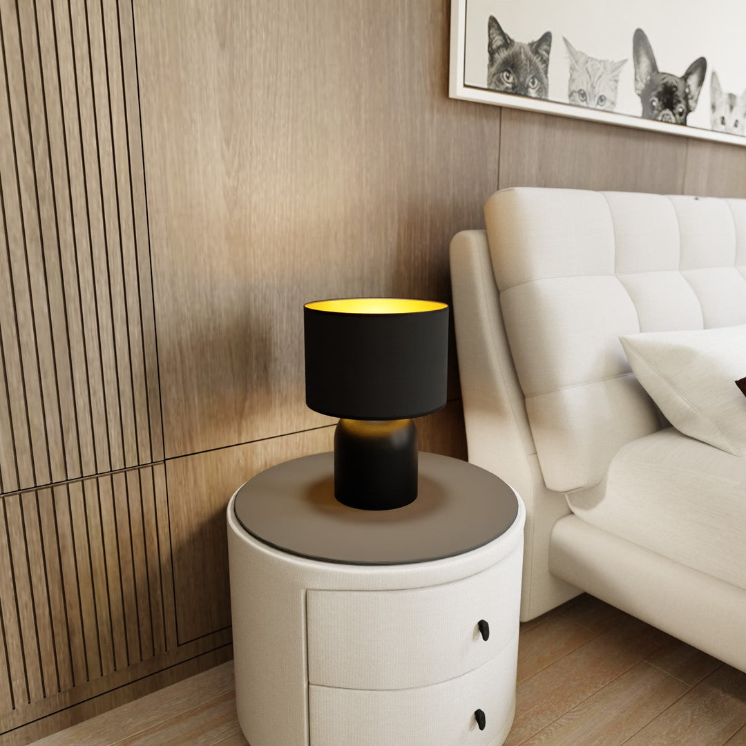 Lampe allumée sur table de chevet, près d'un lit et d'un cadre de chats.