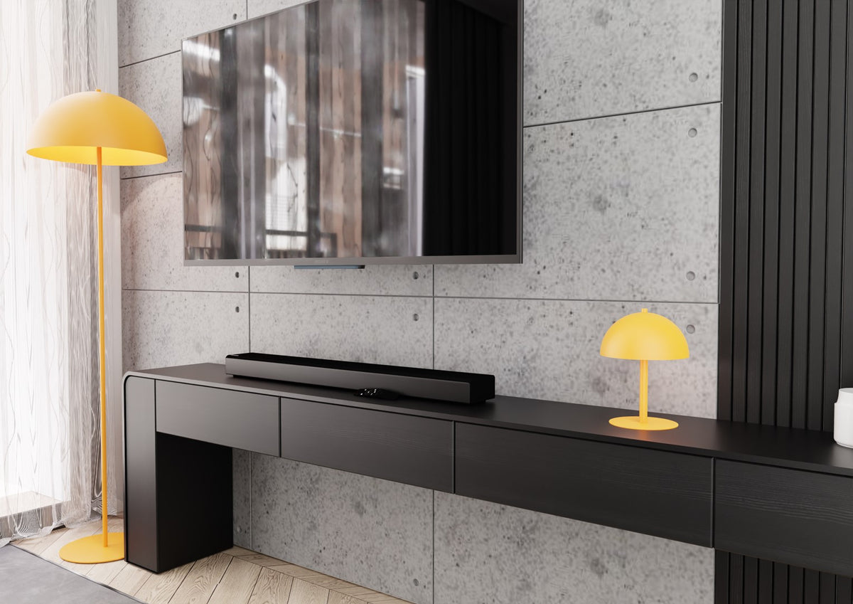 Mise en ambiance sur un meuble TV noir devant un mur béton gris