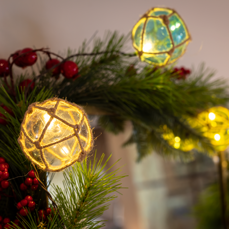Boule lumineuse posée sur des branches de sapin et des baies rouges