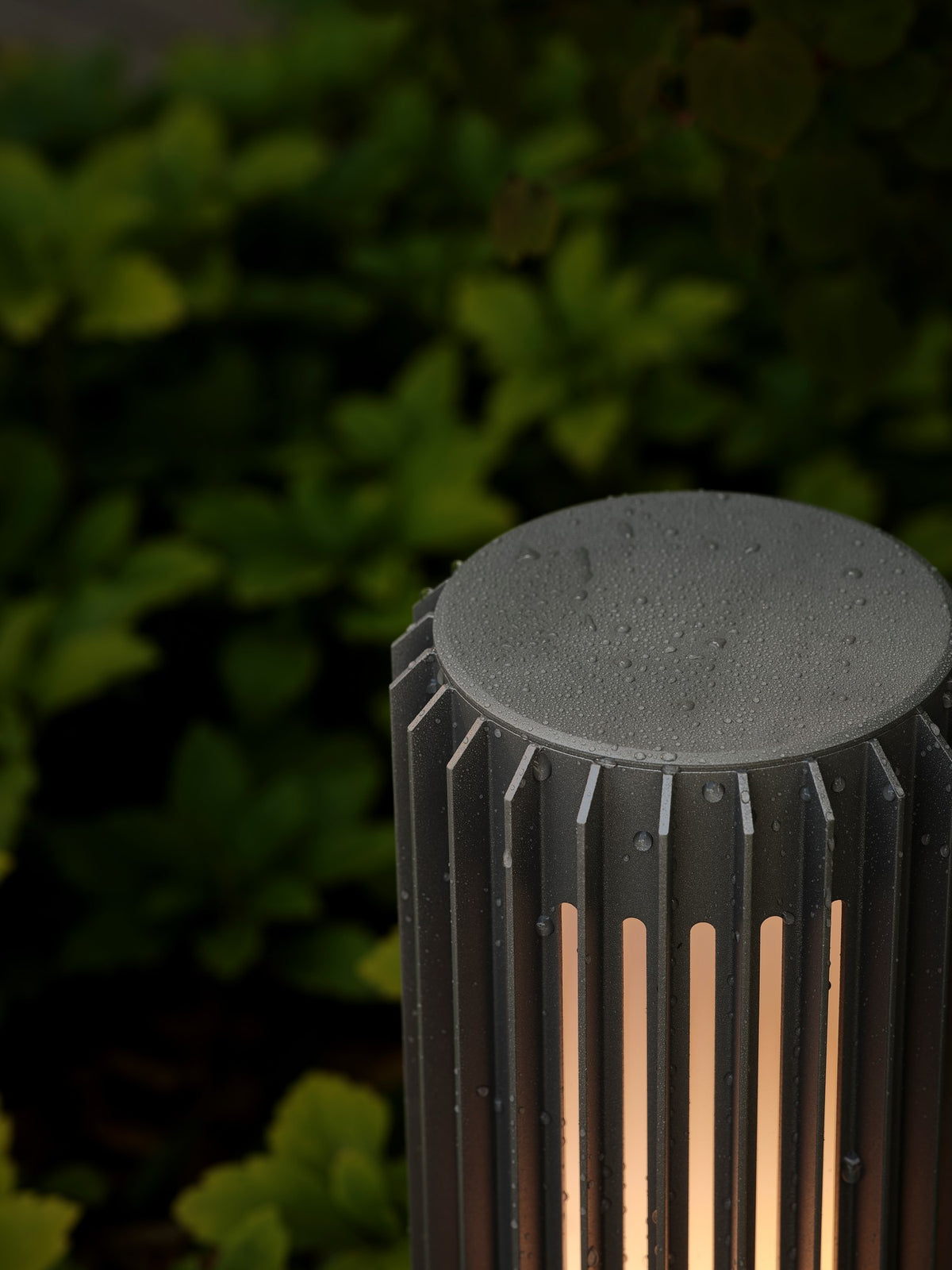 Détail du sommet de la borne avec gouttes d'eau, finition noire et fentes lumineuses.