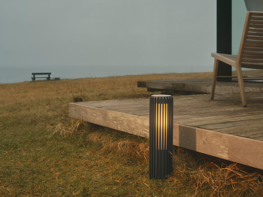 Borne installée sur une terrasse en bois, près de l'herbe et face à la mer.
