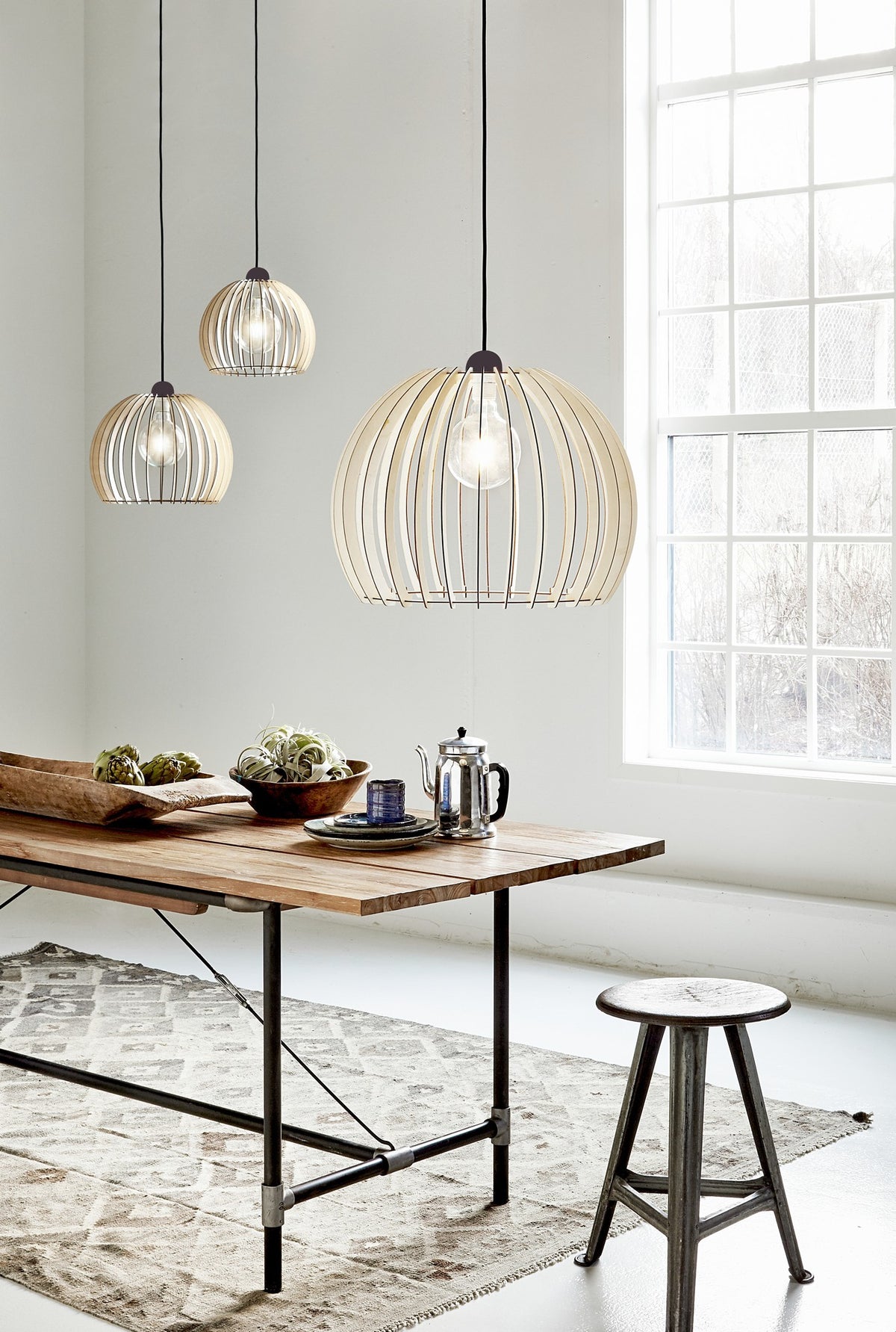 Mise en ambiance : trois suspensions en bois suspendues au-dessus d'une table en bois