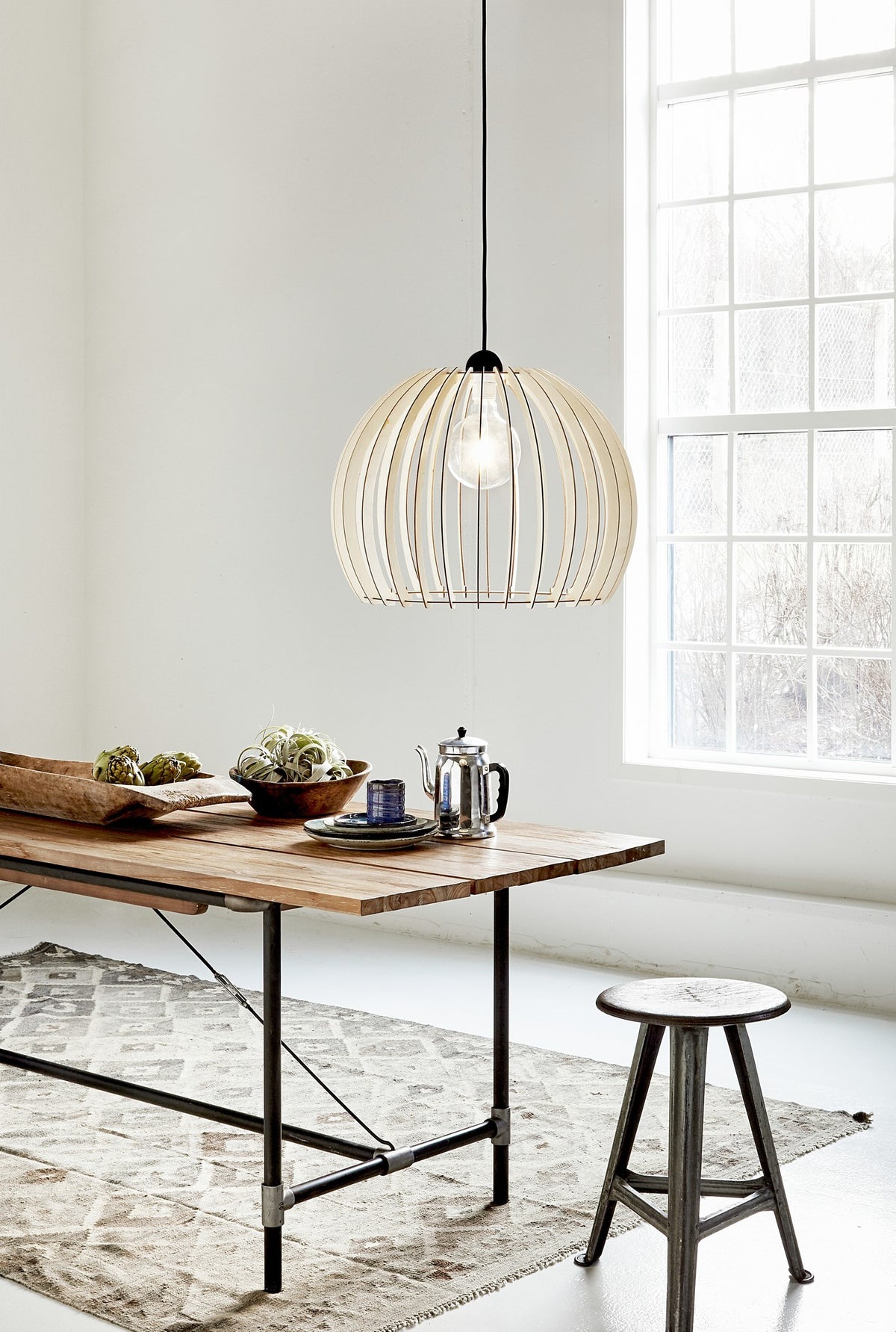 Suspension en bois installée au-dessus d'une table en bois dans une pièce lumineuse.