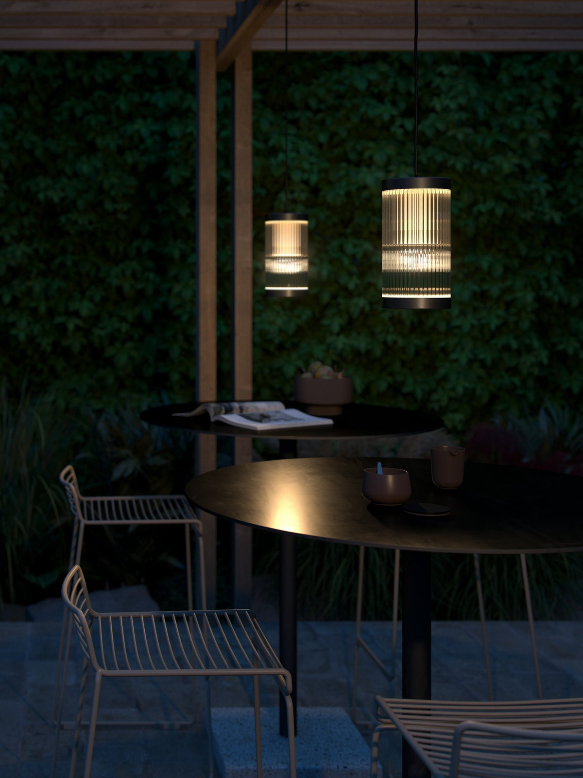 Mise en ambiance nocturne sous une pergola en bois, deux suspensions éclairent une table