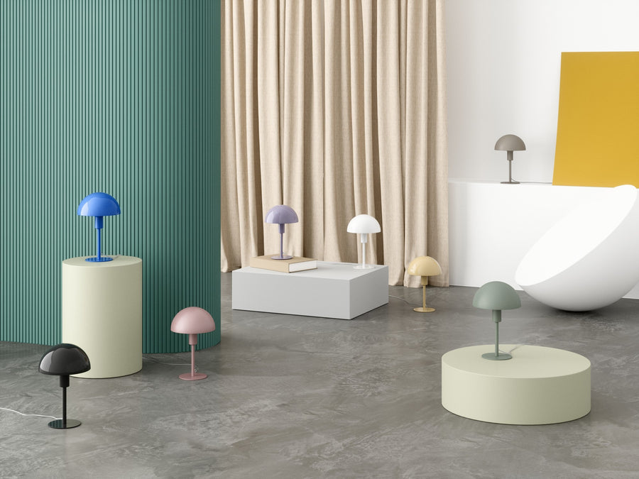 Scène décorative présentant plusieurs lampes colorées sur socles et mobilier design