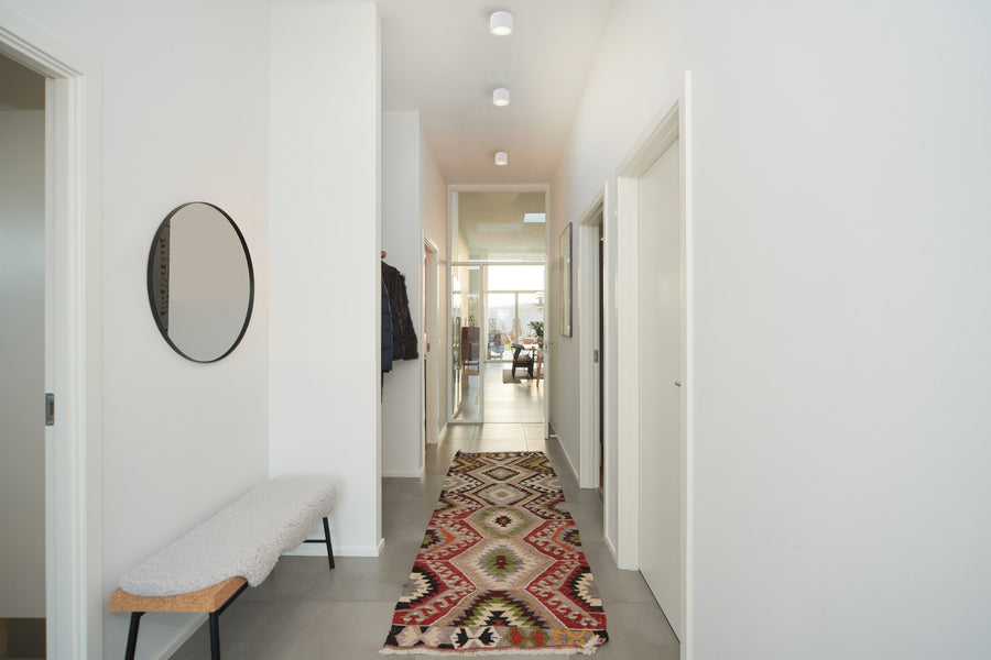 Couloir moderne éclairé par des spots LED ronds blancs en saillie.