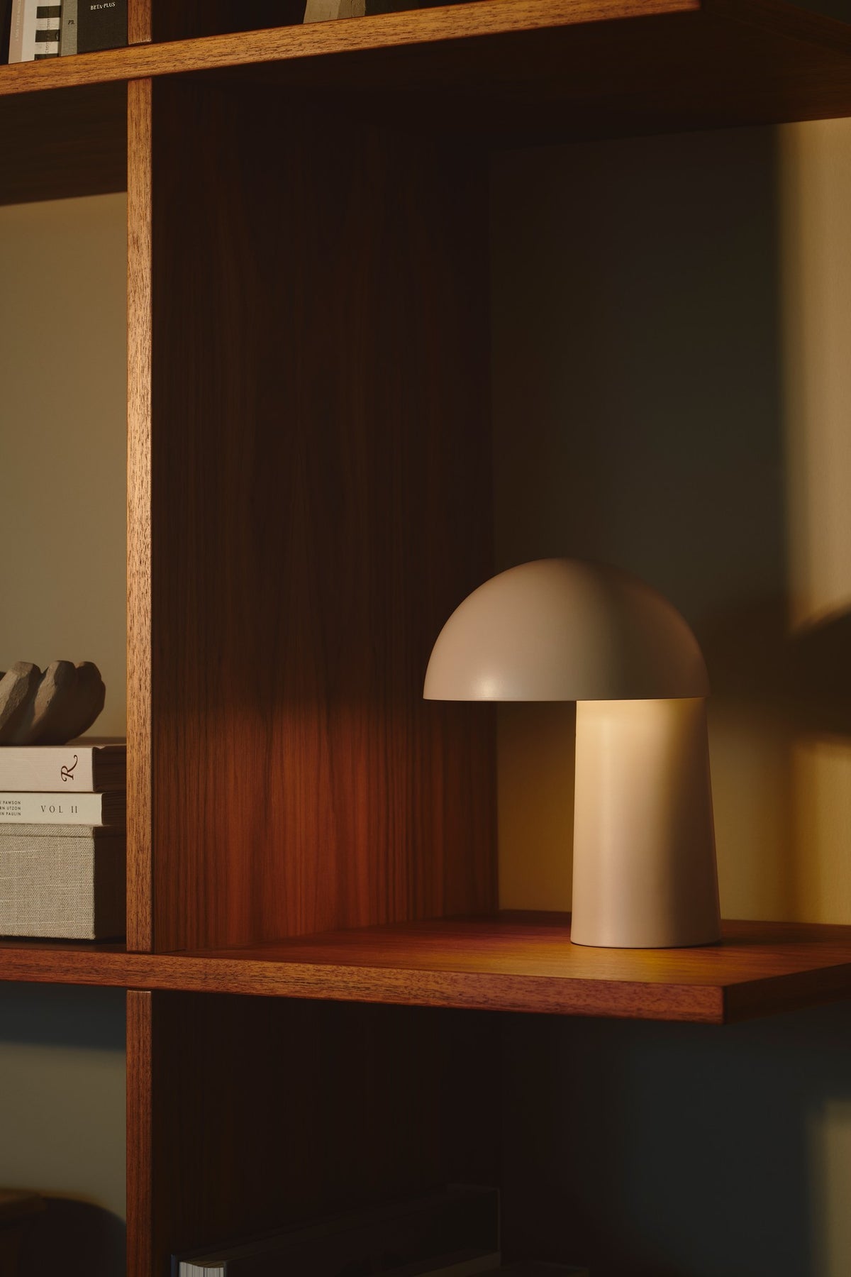Lampe beige allumée posée sur une étagère en bois, lumière chaude