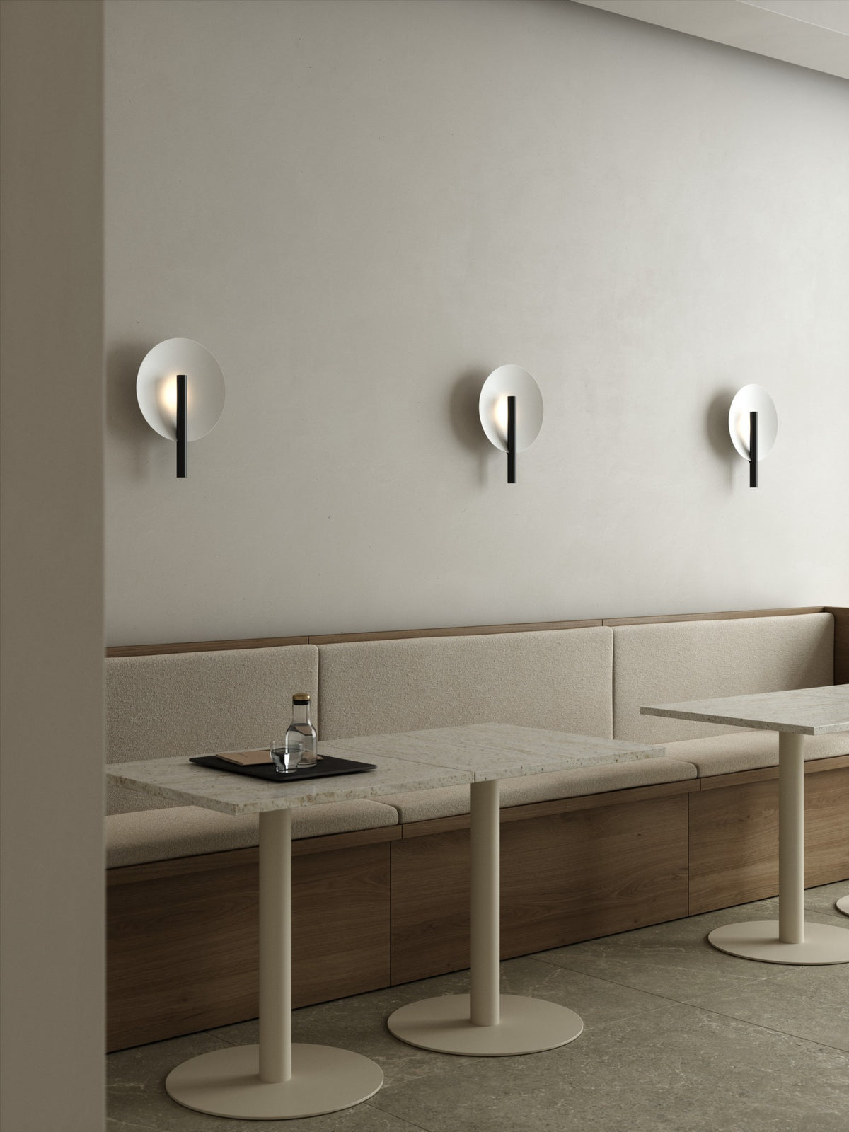 Mise en ambiance dans un café, trois appliques alignées au-dessus d'une banquette