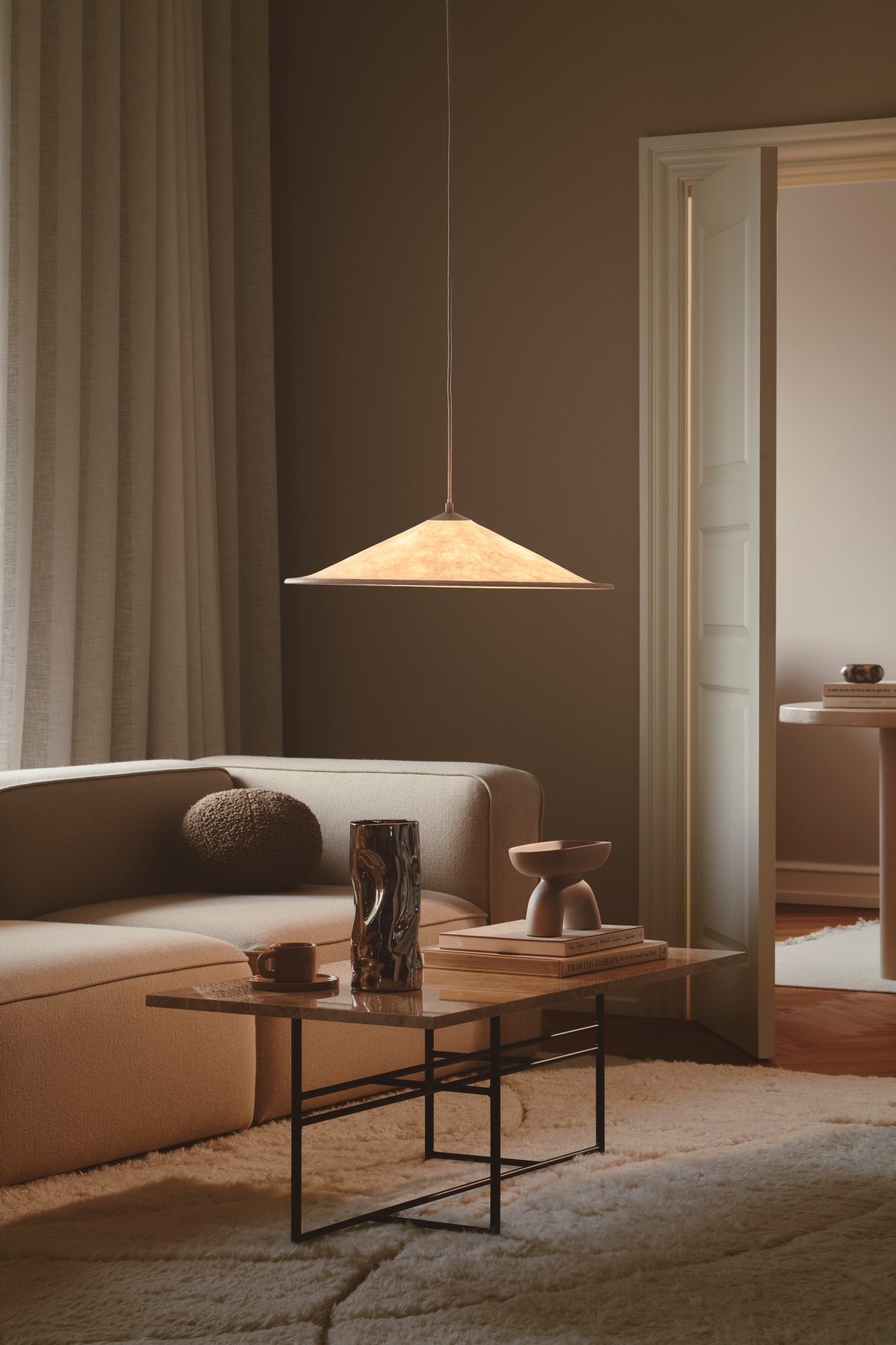 Ambiance salon chaleureuse avec suspension allumée au-dessus d'une table basse.