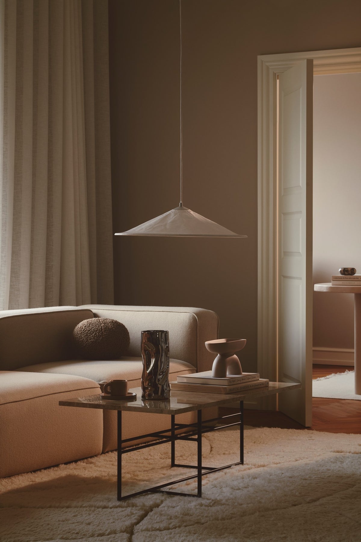 Vue en situation du luminaire suspendu au-dessus du canapé dans un intérieur.