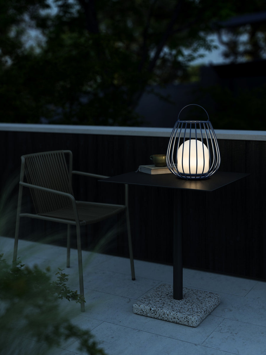 Lanterne éclairée sur une table de terrasse au crépuscule, mise en ambiance extérieure