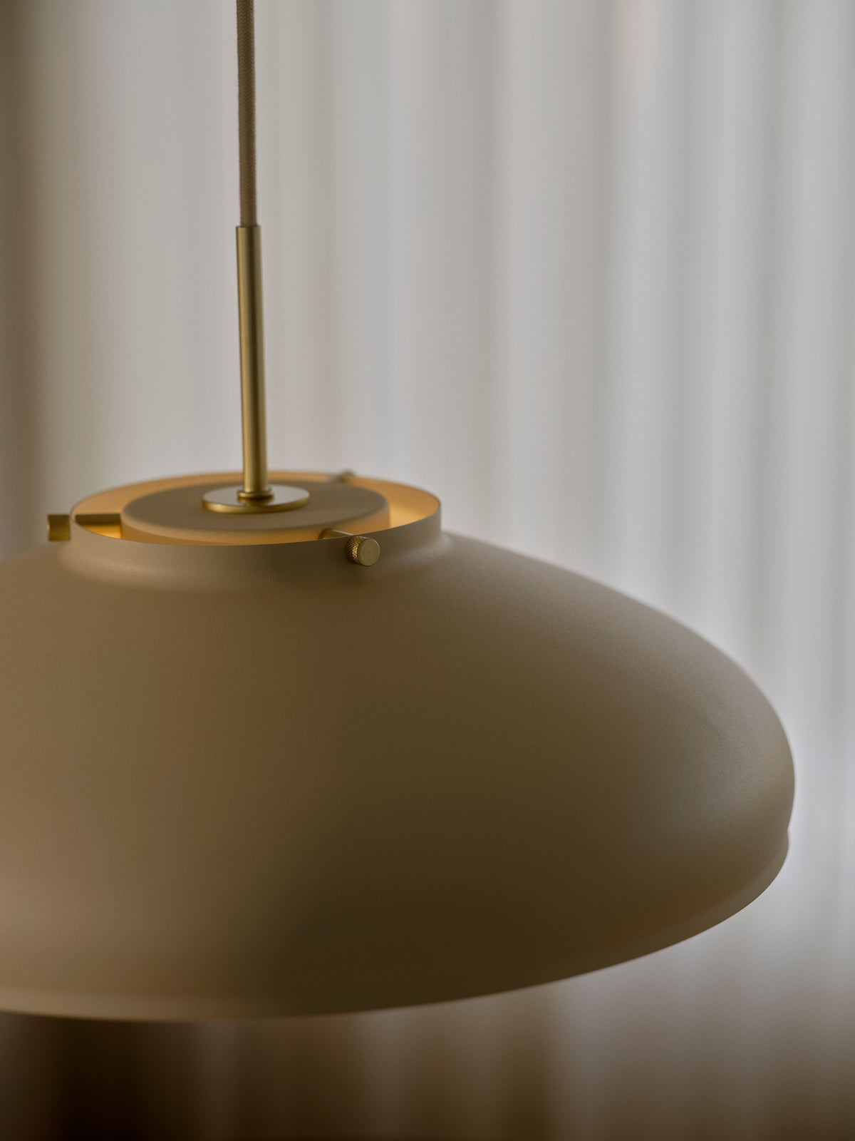 Détail de la finition : abat-jour beige, vis dorées et tige métallique apparentes.