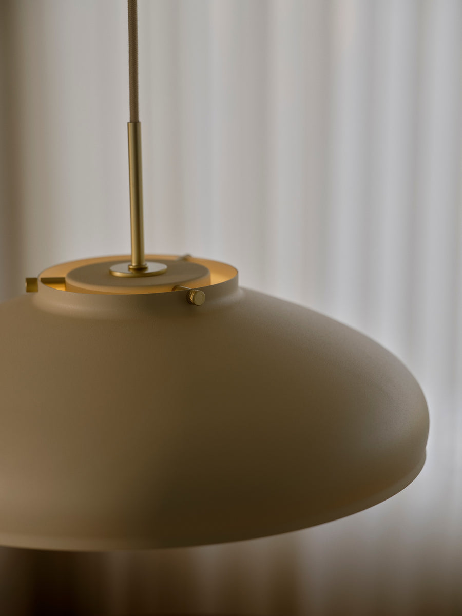 Détail de la finition : abat-jour beige, vis dorées et tige métallique apparentes.