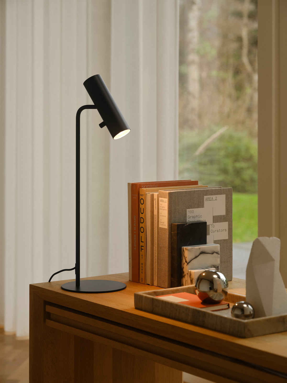 Ambiance intérieure : lampe noire éclairée près de livres et d'objets décoratifs.