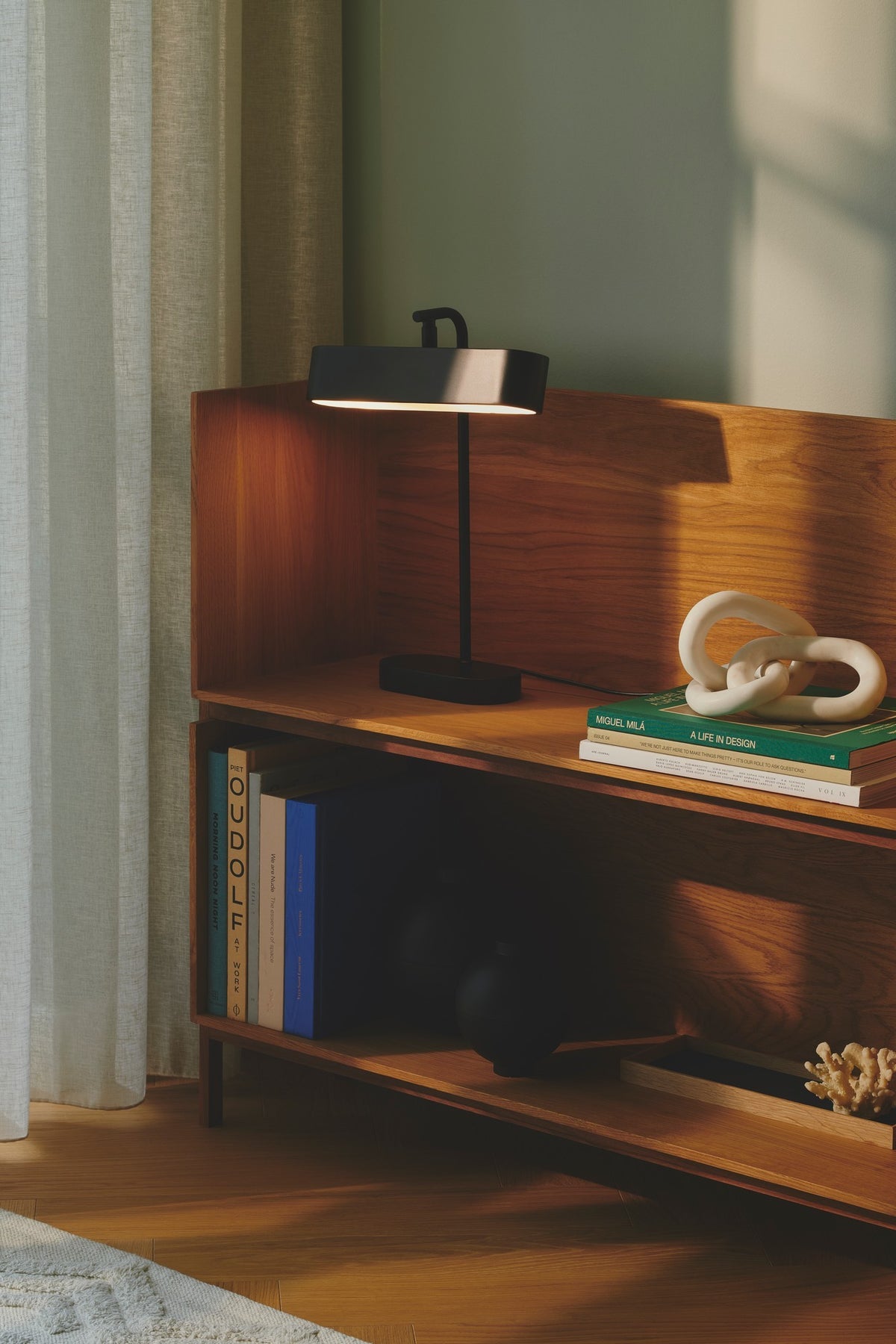 Mise en ambiance sur une étagère en bois avec livres et rideau clair
