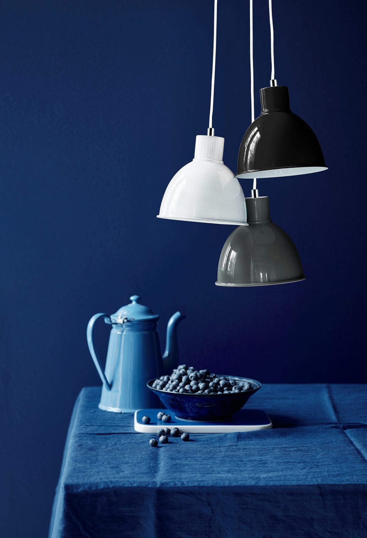 Mise en ambiance bleue avec suspensions, théière et myrtilles sur une table
