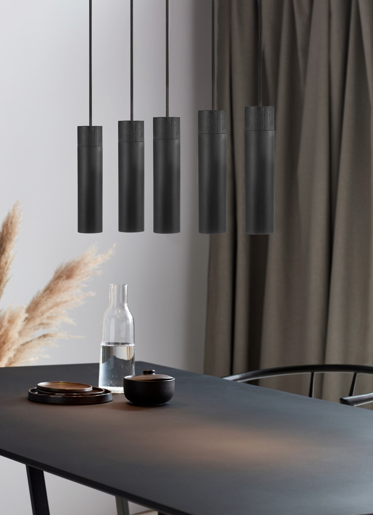 Mise en ambiance au-dessus d'une table noire avec objets décoratifs et rideaux.