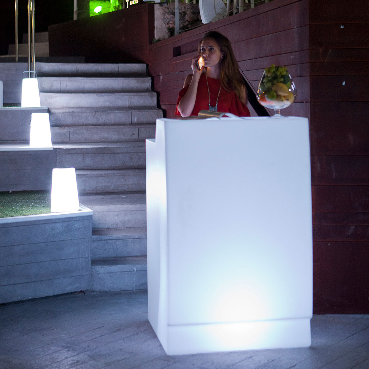 Lampe nomade blanche posée sur des marches en béton, ambiance extérieure de soirée