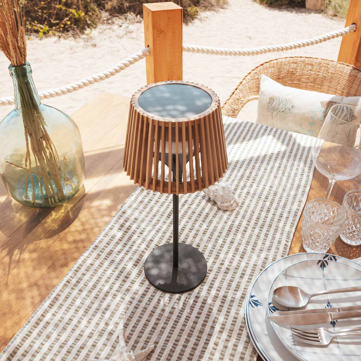 Lampe posée sur une table extérieure en bois, décor de bord de mer
