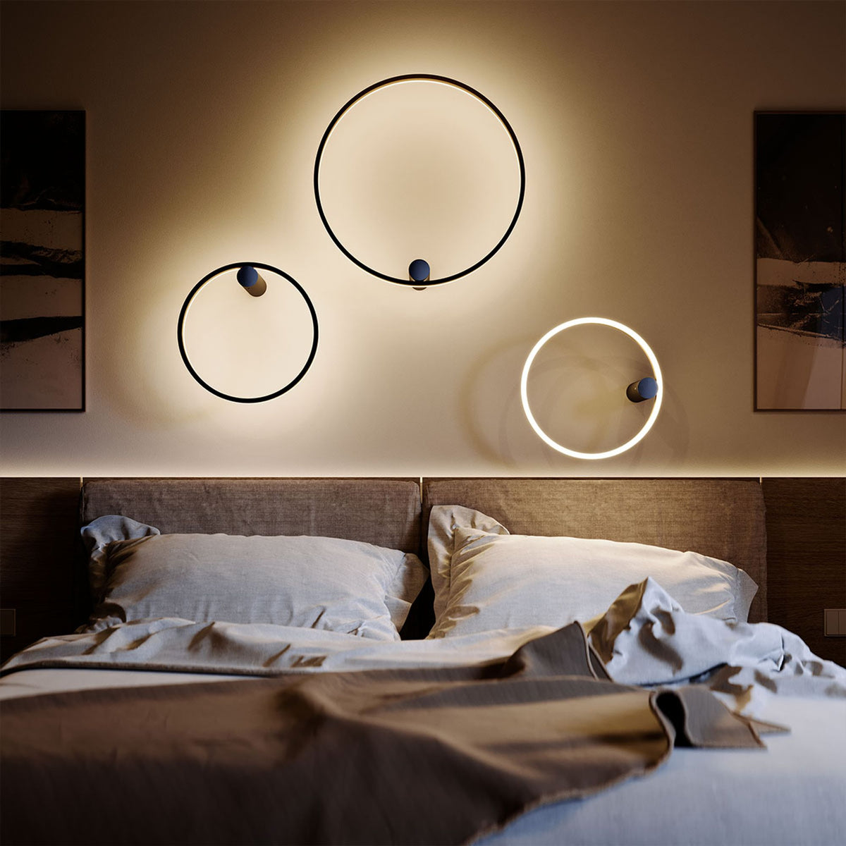Trois appliques murales en anneau LED éclairent le mur derrière une tête de lit