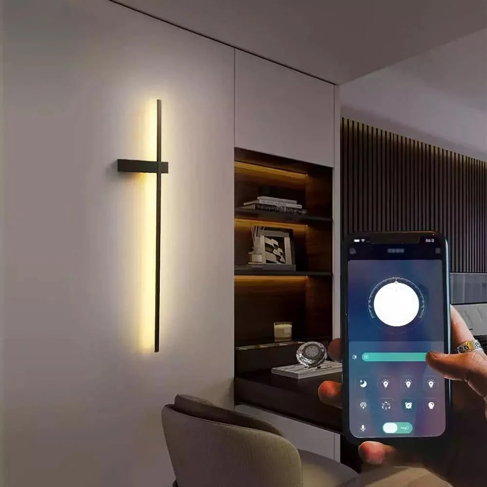Lampe murale allumée près d'une étagère, main tenant un smartphone affichant l'application