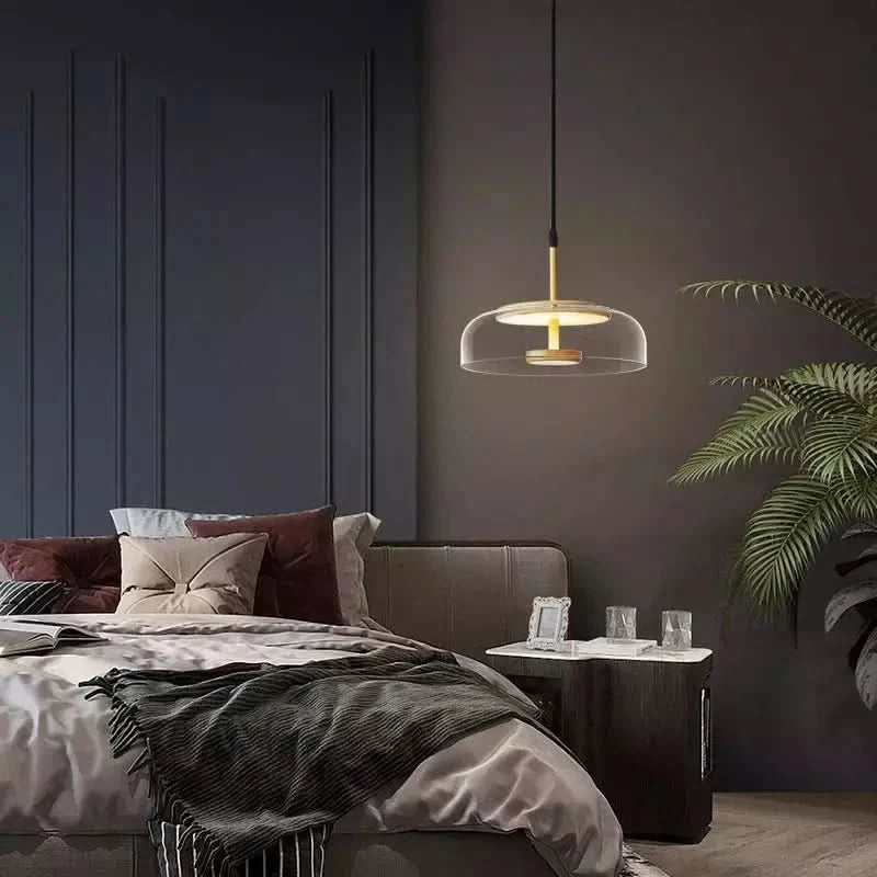 Une suspension dorée éclaire une table de chevet dans une chambre à coucher, lumière chaude