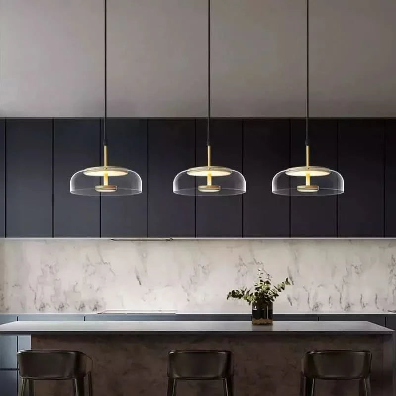 Trois luminaires identiques suspendus au-dessus d'un îlot de cuisine, crédence en marbre