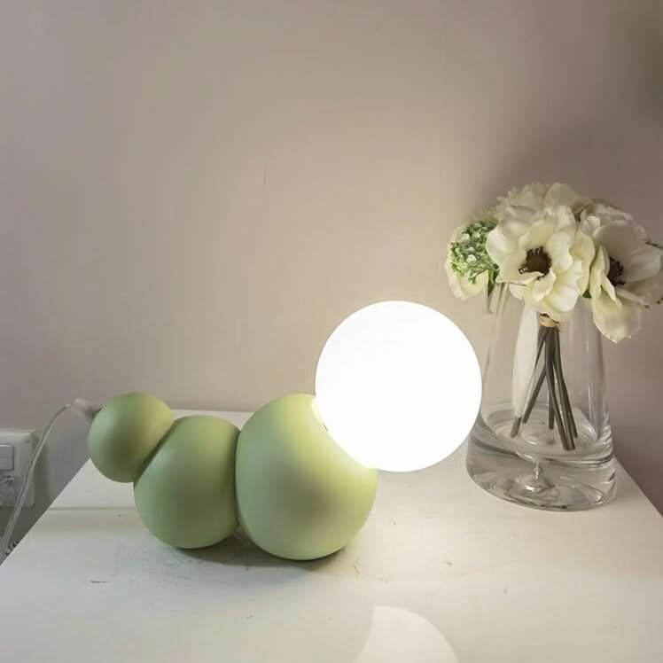 Lampe vert d'eau allumée près d'un vase de fleurs blanches