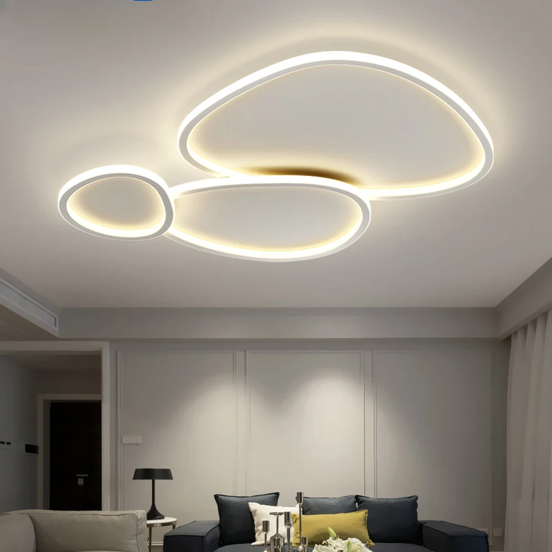 Luminaire plafond allumé au-dessus d'un canapé gris et coussins colorés