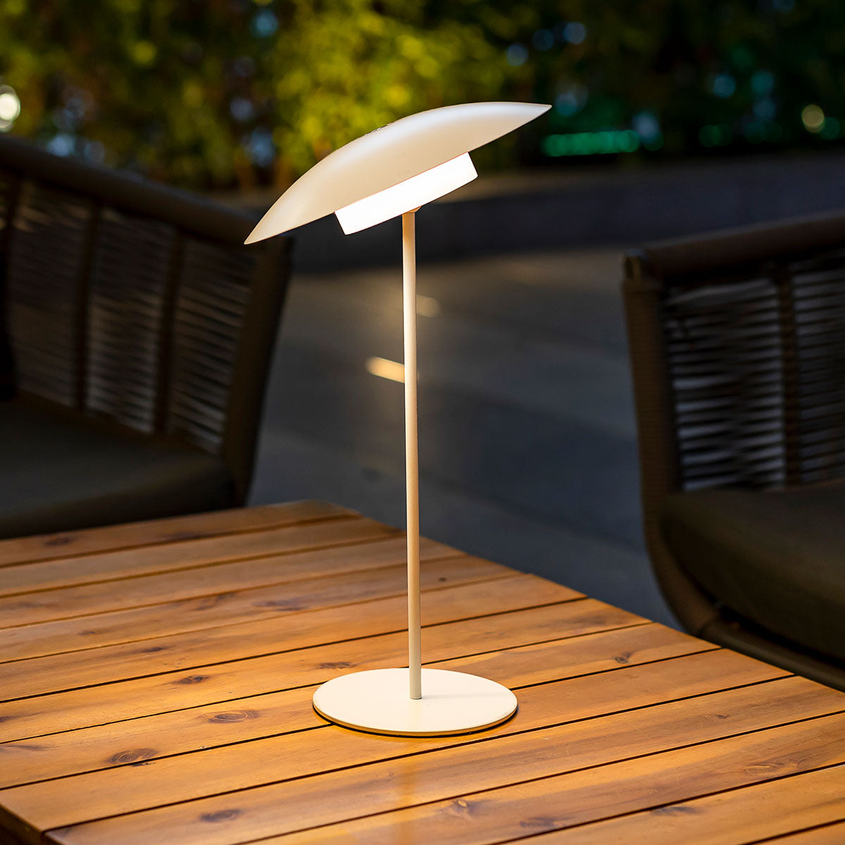 Lampe blanche de profil sur table en bois, abat-jour incliné vers le bas