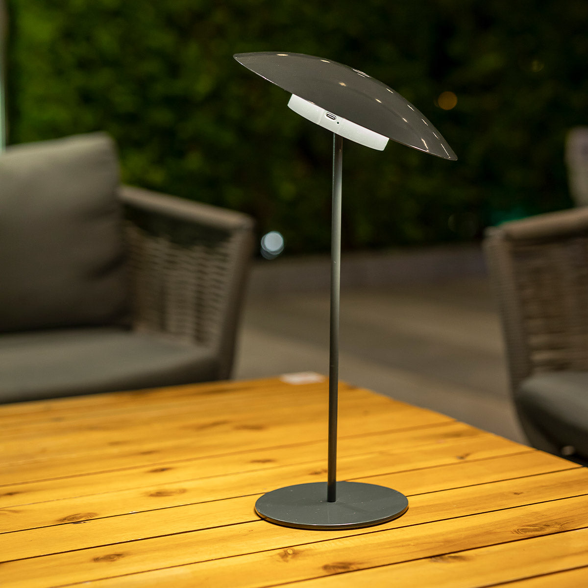 Lampe anthracite posée sur table, port de charge visible sous l'abat-jour