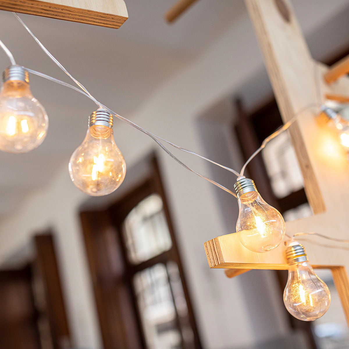 Détail des ampoules à filament suspendues devant une structure en bois, intérieur lumineux