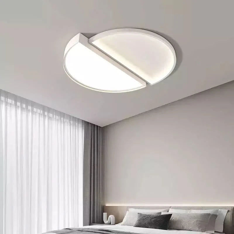 Plafonnier rond demi-lune blanc éclairé au-dessus d'un lit