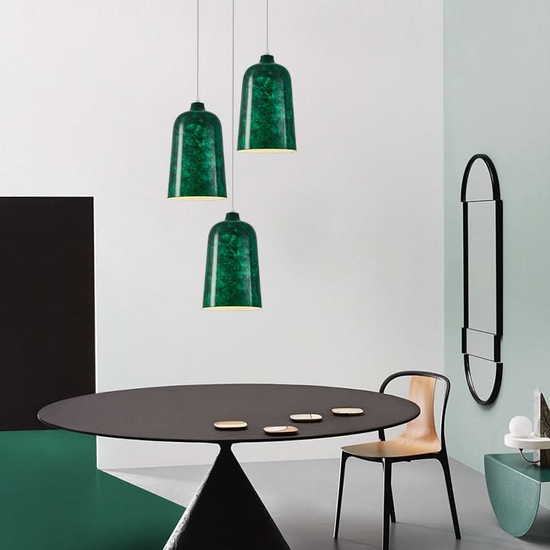 Trois suspensions vertes suspendues au-dessus d'une table noire ovale, miroir mural.