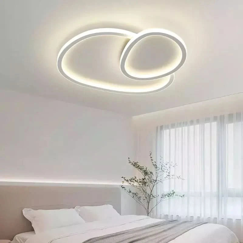 Plafonnier rond éclairé dans une chambre blanche près du lit et rideaux