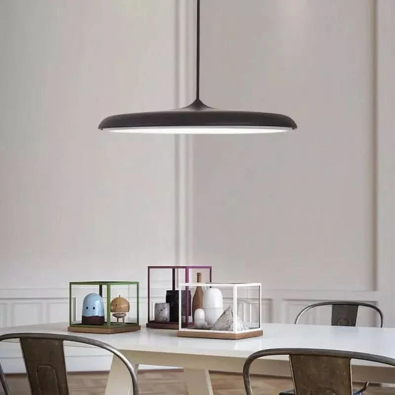 Suspension noire allumée au-dessus d'une table avec objets décoratifs.