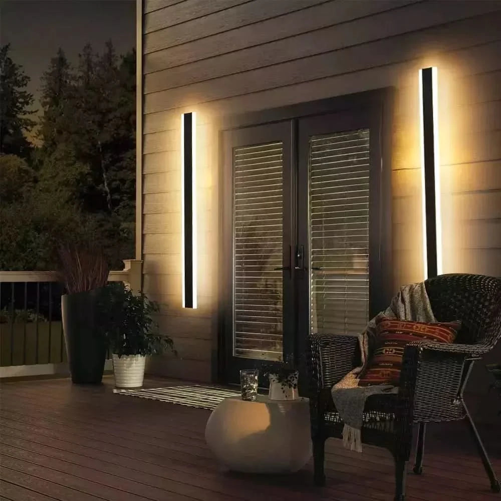Deux appliques linéaires encadrant une porte-fenêtre sur une terrasse en bois