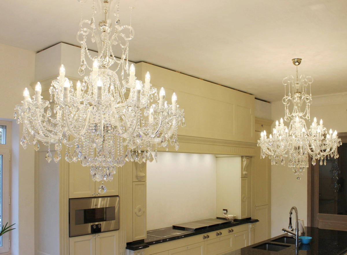 Vue rapprochée du lustre en cristal devant les meubles de cuisine beige et blancs