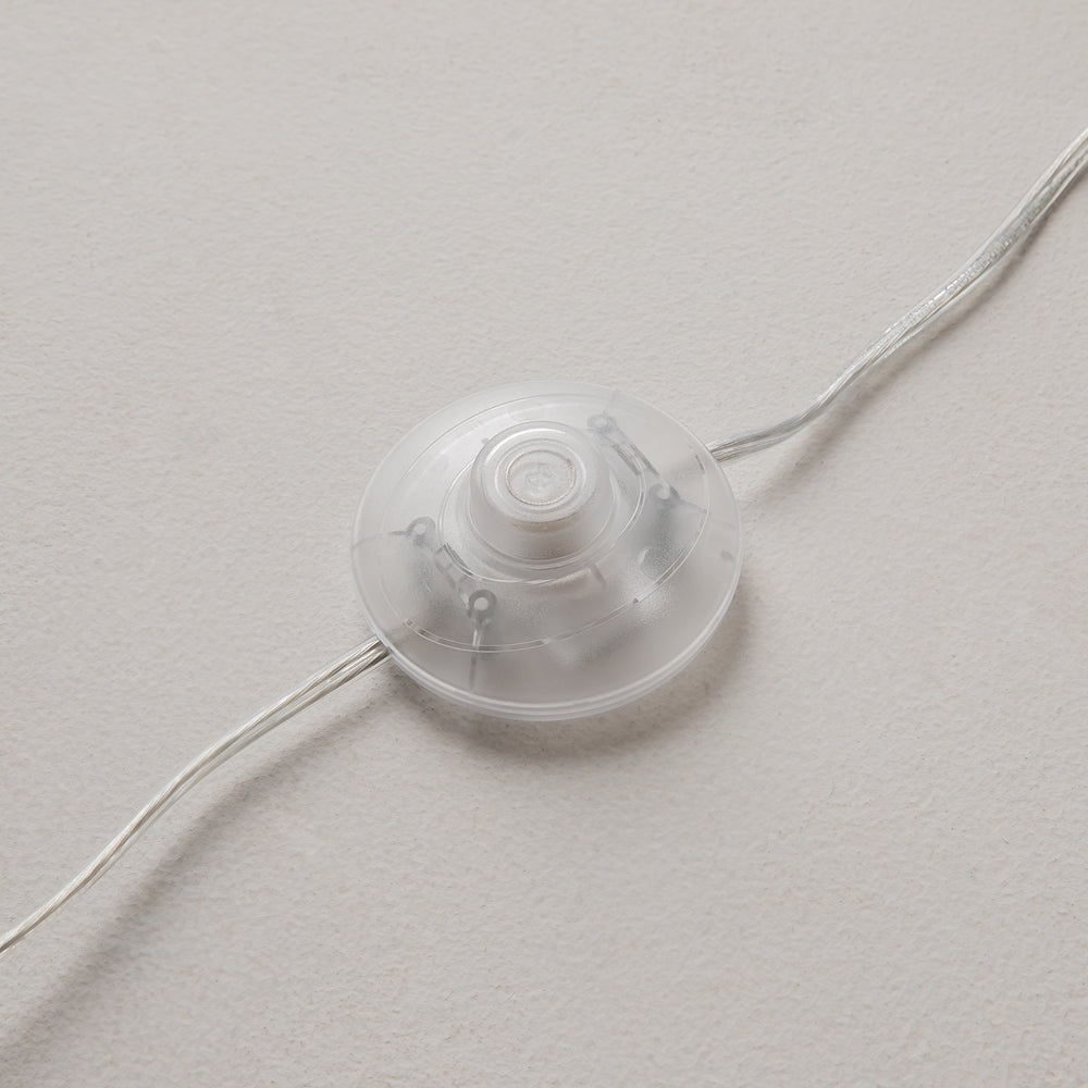 Détail du variateur rond transparent posé au sol avec le câble d'alimentation.