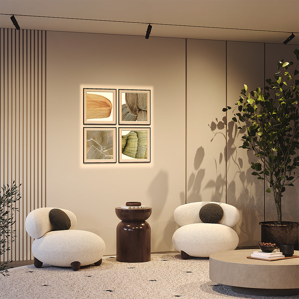 Mise en ambiance salon avec fauteuils blancs, cadres éclairés et plante